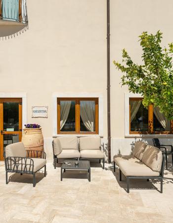 Espace détente extérieur avec chaises, tables, plantes et un panneau 'Réception'.