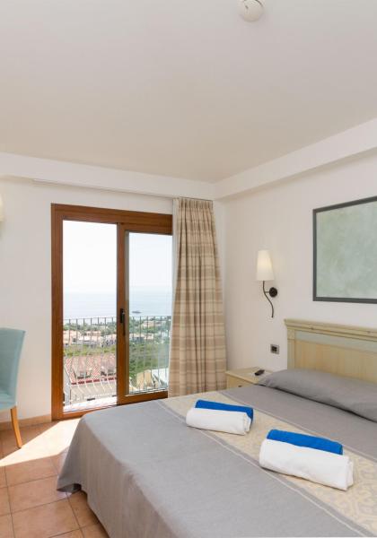 Helles Zimmer mit Meerblick, Doppelbett und Flachbildfernseher.