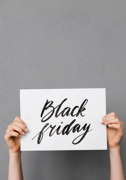 Cartello con scritta 'Black Friday' tenuto da mani su sfondo grigio.