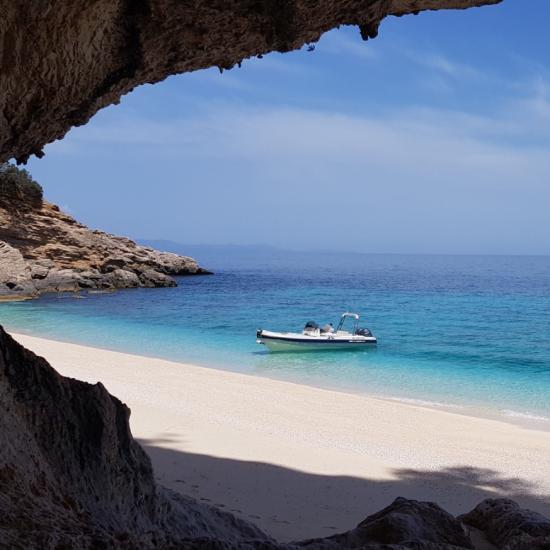 Plage déserte, mer turquoise, bateau solitaire, ciel clair, atmosphère de paix absolue.