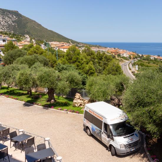 Vue côtière avec mer bleue, collines vertes et un van blanc.