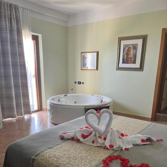 Chambre romantique avec cygnes en serviettes, pétales de roses et jacuzzi.