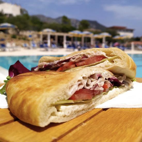 Sandwich savoureux au bord de la piscine, soleil et détente estivale.