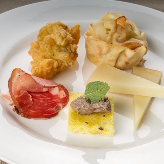 Assiette élégante avec amuse-bouches variés : fromages, charcuteries et frits.