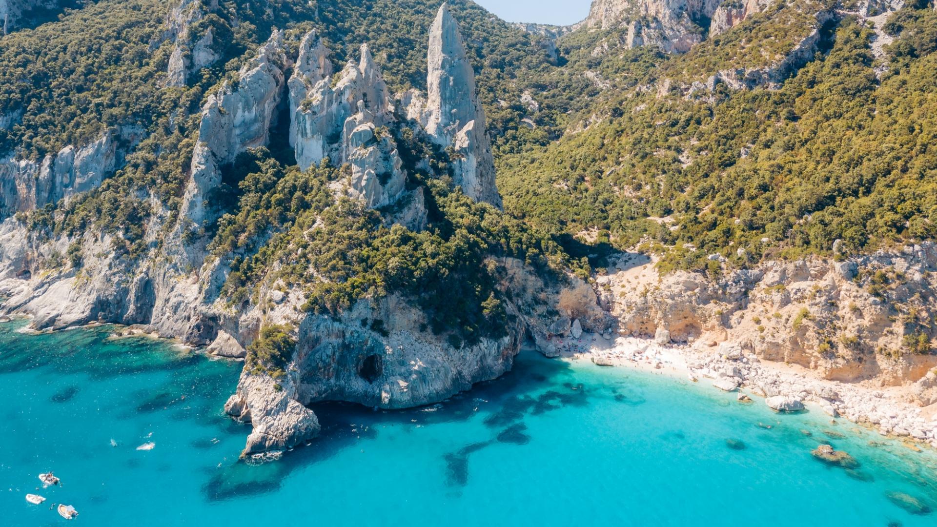 Una vista aerea di una spiaggia rocciosa con acque cristalline blu dal carattere sereno e rilassante.