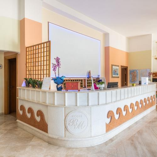 Una hall d'albergo con una scrivania di ricezione bianca.