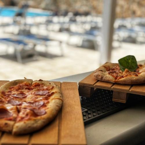 Un paio di pizze posizionate su un tavolo di legno e un’atmosfera accogliente.