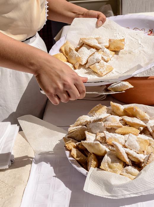 Mani servono dolci fritti zuccherati, evocando tradizione e dolcezza.