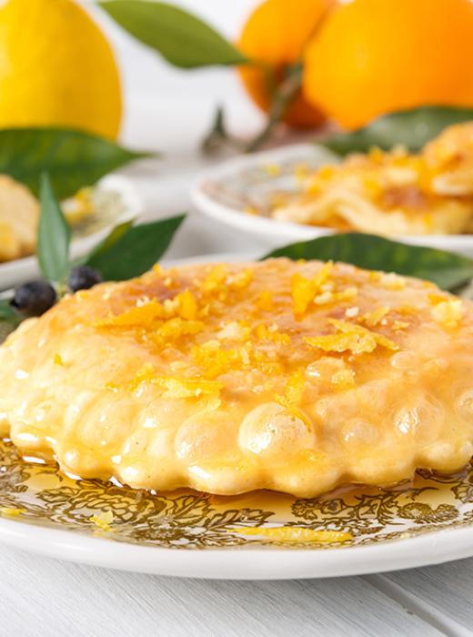 Dolci fritti, miele e agrumi evocano calore e tradizione.