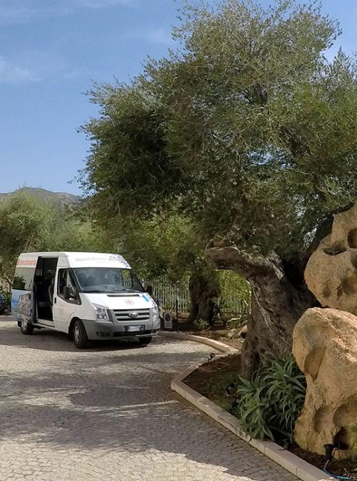 Viale sereno con furgone e rocce sotto un cielo azzurro.