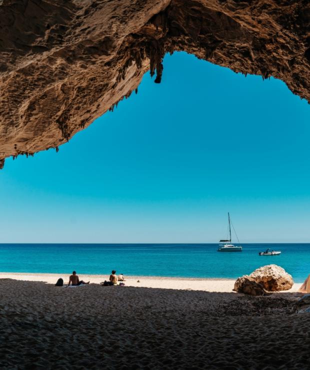 Un gruppo di persone sedute su una spiaggia sotto una grotta e un fascino semplice e ospitale.