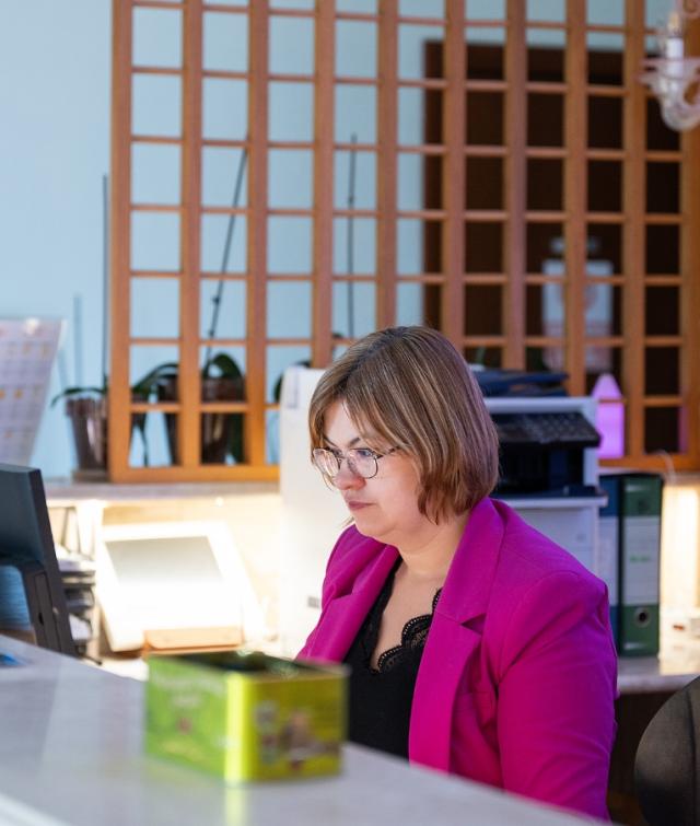 Una donna seduta a una scrivania che lavora su un laptop con un fascino semplice e ospitale.