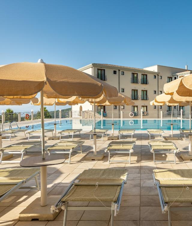 Un gruppo di poltrone e ombrelloni vicino a una piscina con un fascino accogliente.