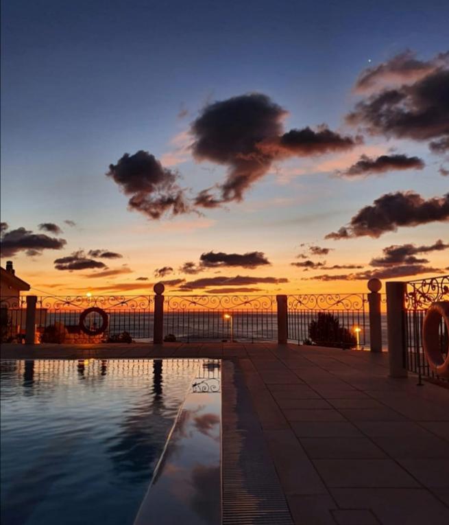 Tramonto mozzafiato riflesso in piscina, cielo arancione e nuvole scure.