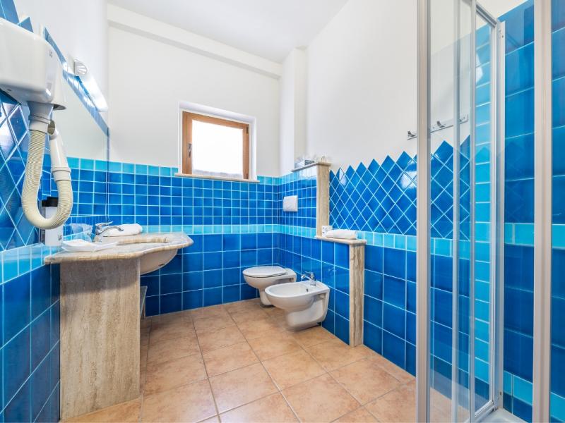 Un bagno con piastrelle blu sulle pareti dal gusto moderno ed essenziale.