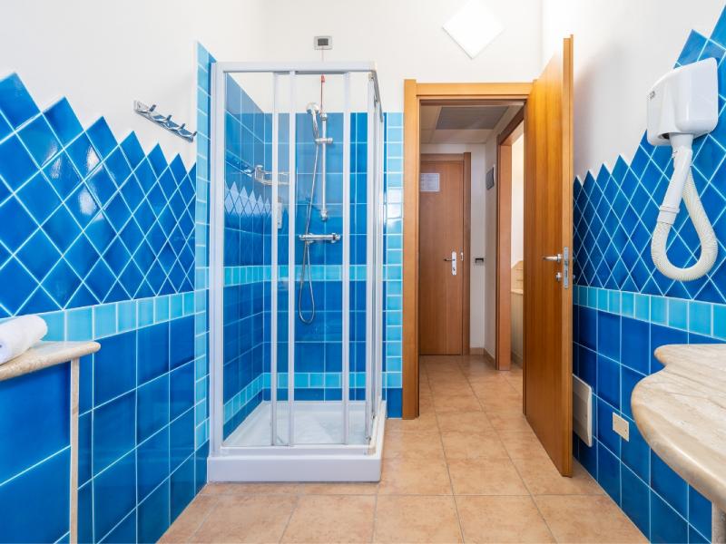 Un bagno con piastrelle blu sulle pareti dal gusto moderno ed essenziale.