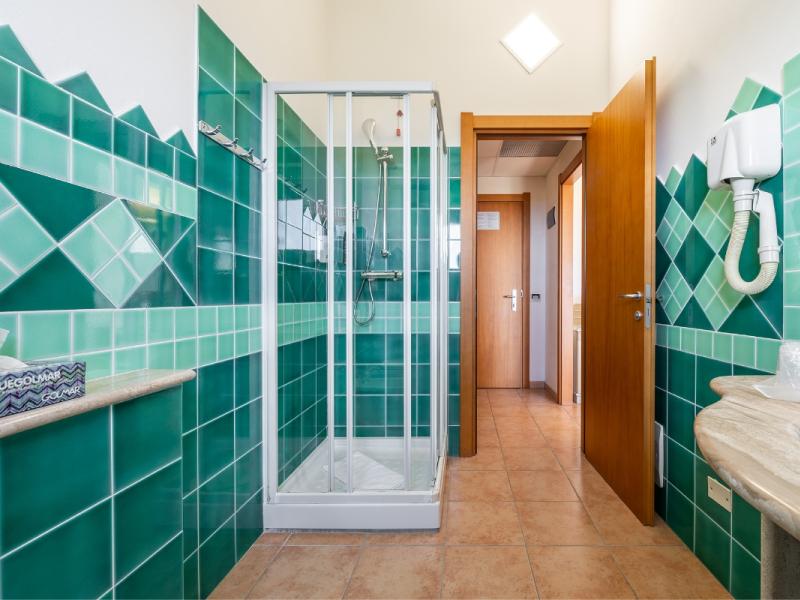 Un bagno con piastrelle verdi sulle pareti con dettagli pratici e armoniosi.