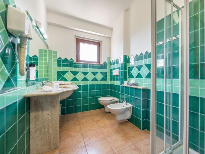 Un bagno con piastrelle verdi con bagno e lavandino, linee pulite e funzionali.