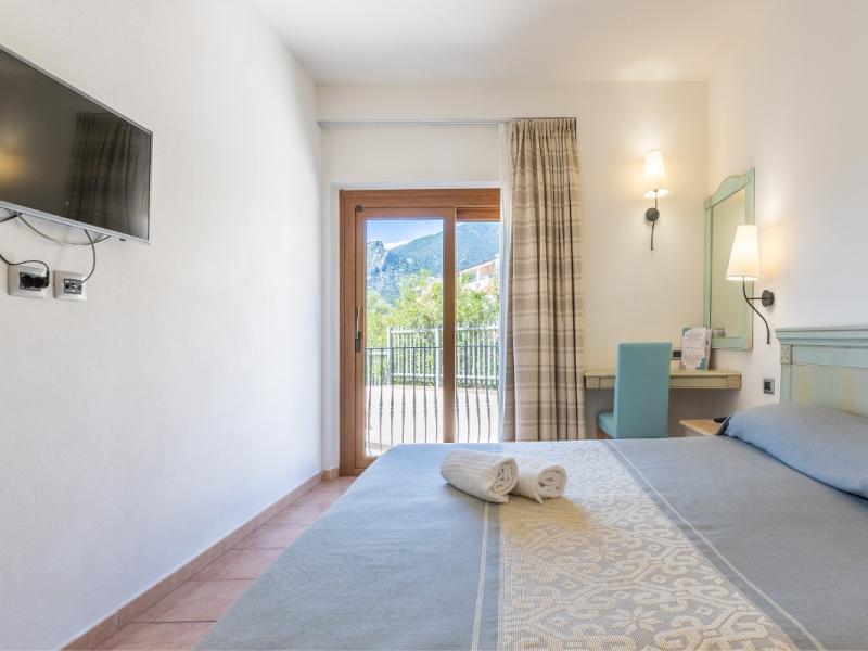 Una camera da letto con un grande letto e un televisore a schermo piatto con colori freschi e invitanti.