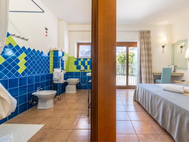 Un bagno con un muro in piastrelle blu e verde con linee pulite e funzionali.