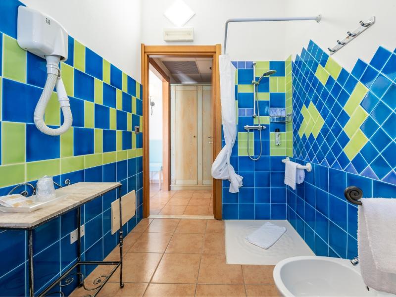 Un bagno con piastrelle blu e verdi sulle pareti con linee pulite e funzionali.