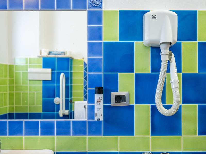 Un bagno con un muro in piastrelle blu e verde con linee pulite e funzionali.