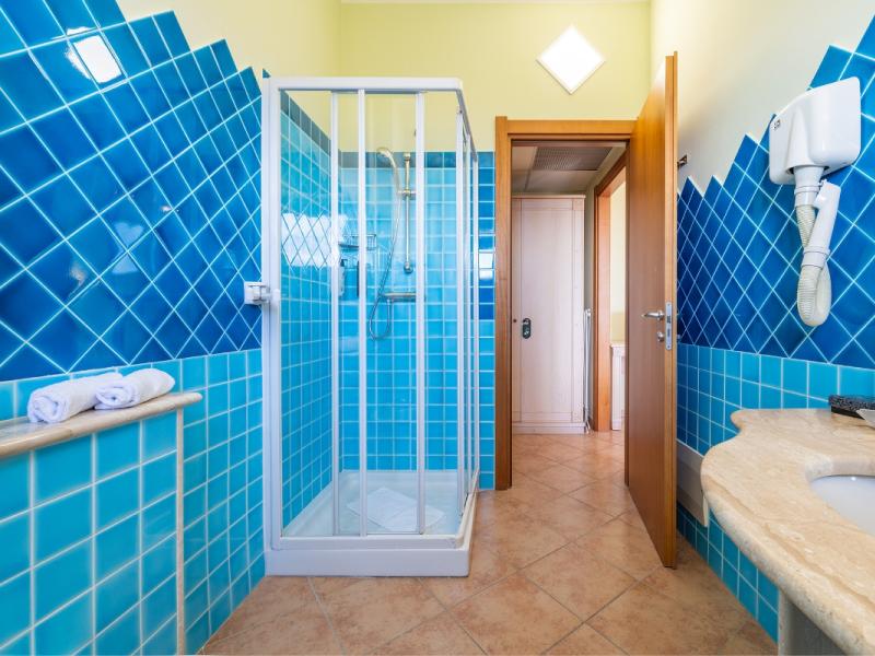 Un bagno con piastrelle blu sulle pareti dal gusto moderno ed essenziale.