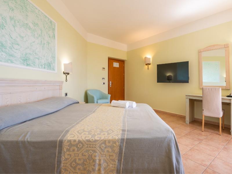 Una camera d'albergo con letto, scrivania e televisione dal gusto curato.