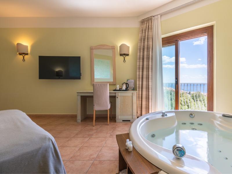 Una camera da letto con una grande vasca da bagno e un televisore con un design semplice e curato.