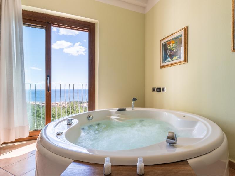 Una vasca da bagno con vista sul mare e un balcone con dettagli pratici e armoniosi.