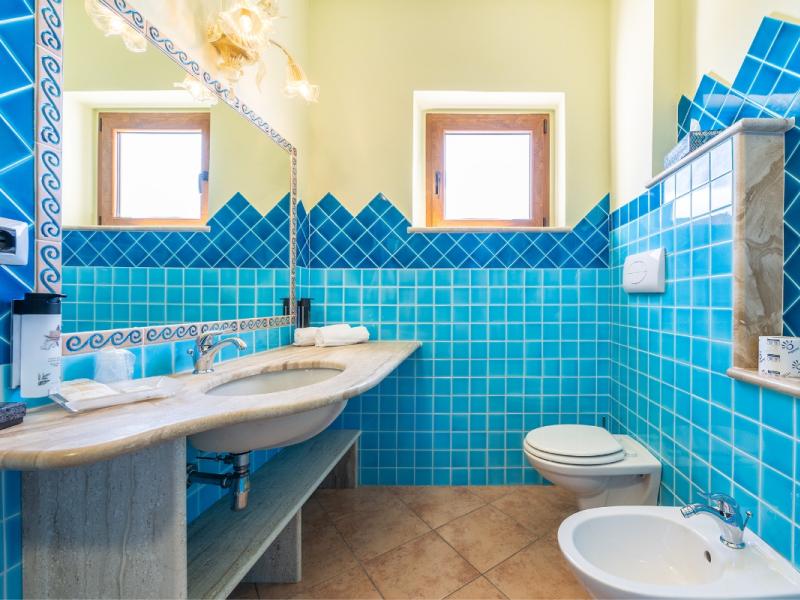 Un bagno in piastrelle blu con lavandino e bagno, dettagli pratici e armoniosi.