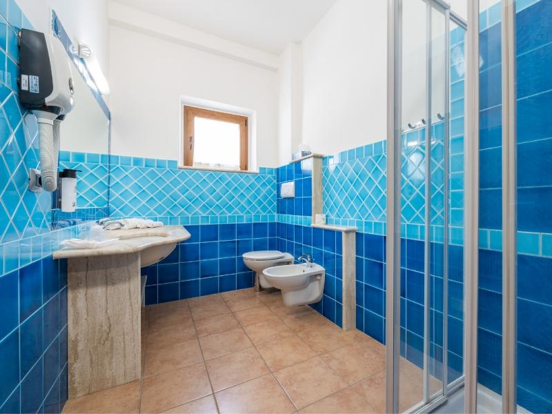 Un bagno con piastrelle blu sulle pareti dal gusto moderno ed essenziale.